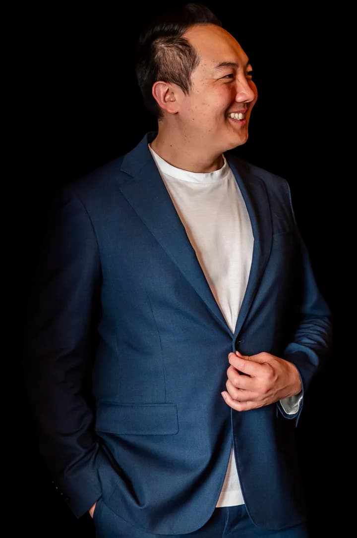 John Lee, smiling, in a navy jacket over a white T-shirt